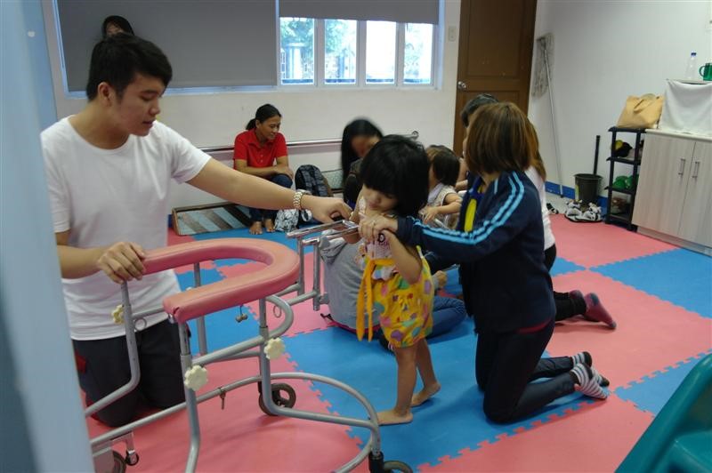 A young Filipino girl being supported to walk through the Disabled Therapy Programme.